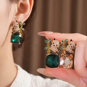 Squisiti orecchini a lobo panda con strass scintillanti e grandi cristalli color smeraldo.