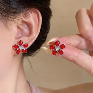 Detailed close-up of elegant red flower stud earrings with vibrant zircon crystals shown on ear