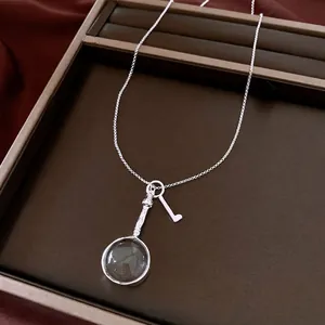 Collana d'argento vintage con pendente a forma di lente d'ingrandimento e chiave.