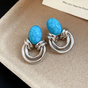 Dettaglio degli orecchini d'argento vintage con pietre ovali di turchese e design retro.
