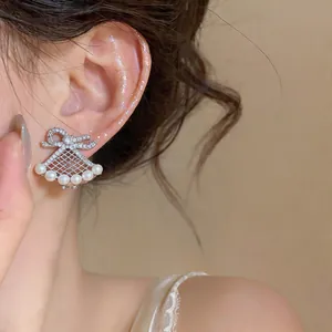 Detailed close-up of an elegant silver bow ear clip with pearls and zircons on model's ear