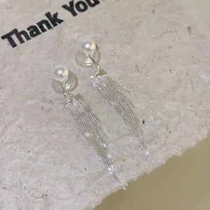 Detailed macro view showing the fine silver tassel chains and white pearls of the earrings