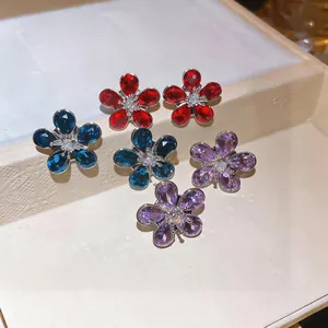 Close-up of sparkling flower-shaped zircon stud earrings in red, blue, and purple