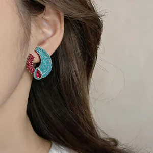 Detailed close-up view of vintage style turquoise and red zircon crescent earrings worn