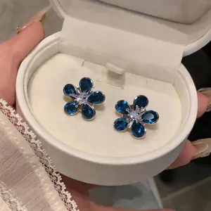 Close-up detail of luxury blue floral zircon stud earrings in a white jewelry box