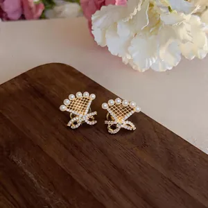 Detail view of 18k gold plated clip-on earrings featuring a delicate bow and pearl design.
