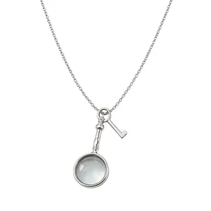 Collana con ciondolo a lente d'ingrandimento retrò e chiave in argento su fondo bianco