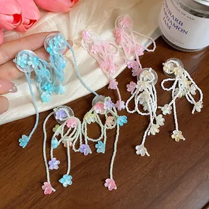 Macro detail of colorful beaded flower tassel earrings with glass petals on a wooden table.