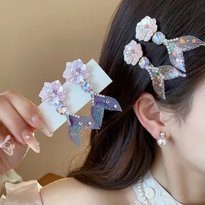 Dettaglio di fermagli per capelli con fiori e coda di sirena con strass lucenti.
