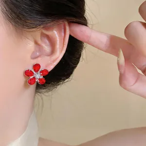 Detailed close-up showing sweet red flower zircon stud earrings worn on an Asian model's ear