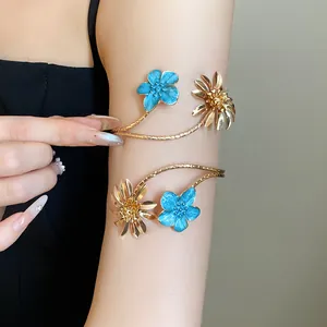 Detailansicht eleganter goldener Armreifen mit blauen Emaille- und Gänseblümchenblüten