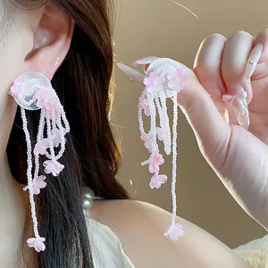 Detailed view of handmade pink glass flower tassel earrings with delicate white beads.