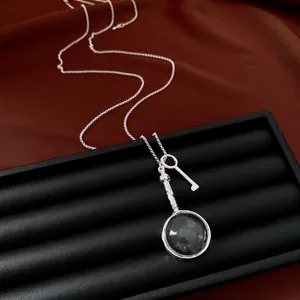 Dettaglio collana argento vintage con chiave e pendente circolare in vetro lucido