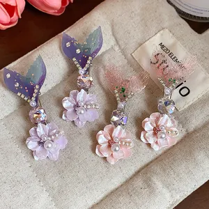 Dettaglio di fermagli per capelli a coda di sirena con fiori in resina, perle e strass