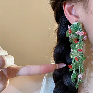 Floral glass leaf tassel earrings worn on ear with elegant forest style design