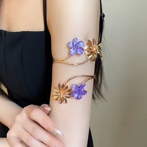 Nahaufnahme eines goldenen Oberarmreifs mit lila Emaille-Blumen im Vintage-Stil für Damen.