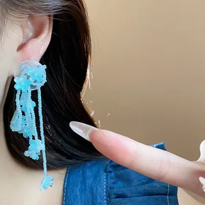 Detailed close-up showing light blue glass flower tassel earrings worn on a model's ear
