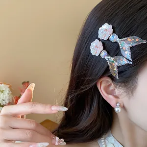 Dettaglio ravvicinato di fermagli per capelli con fiori in resina e coda di sirena glitter