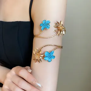 Eleganter Vintage Gold-Blumenarmreif mit blauen Emailleblüten am Arm einer Frau