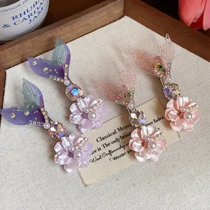 Dettaglio di fermagli per capelli a coda di sirena con fiori in resina e perle