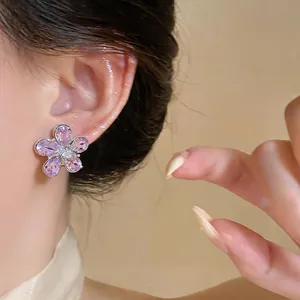 Close-up detail of a sweet flower stud earring with purple zircons worn on model ear