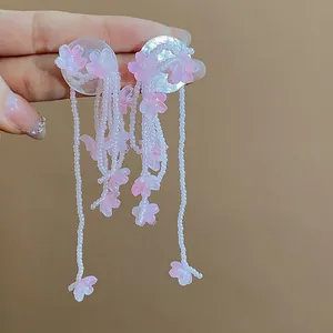 Close-up detail of elegant pink glass flower tassel earrings with white bead strands