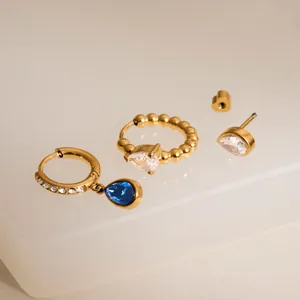 Detailed view of 18k gold-plated earrings set with blue teardrop and clear pear zircons.