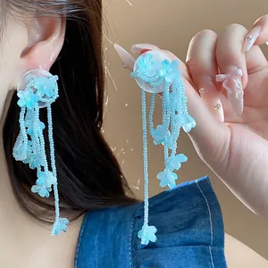 Close-up of elegant light blue glass flower tassel earrings with beaded strands