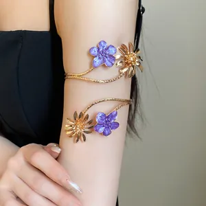 Eleganter Armreif mit lila Emaille- und Goldblumen an einem weiblichen Modell.