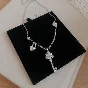 Gros plan d'un collier en zircon argenté avec une clé sur une pochette en velours noir.