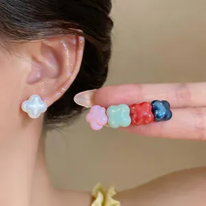 Detailed macro of colorful shell-like flower stud earrings in white, pink and red