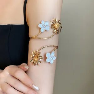 Detailaufnahme eines goldenen Armreifs mit weißer Emaille und Gänseblümchen-Design