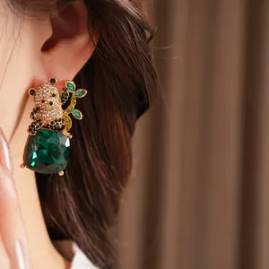 Primo piano di un orecchino a panda con strass scintillanti e una grande gemma verde.