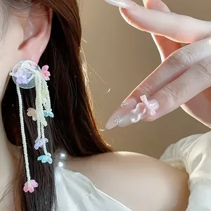 Close-up of elegant floral tassel earrings with pearls on model