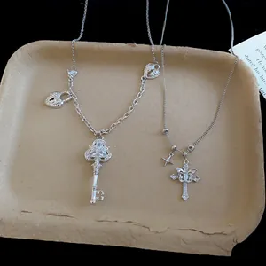 Vue détaillée des colliers en argent avec zircon, clé et croix sur un plateau rustique