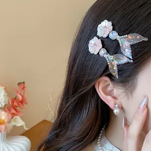 Primo piano della clip per capelli a coda di sirena con fiore in resina e perla lucida