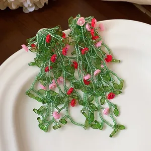 Close-up of forest style handmade beaded flower tassel earrings with green leaves