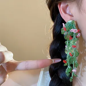 Macro detail showing forest style beaded flower tassel earrings on a model's ear
