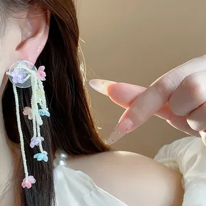 Close-up of elegant glass flower and pearl tassel earrings shown on a model's ear