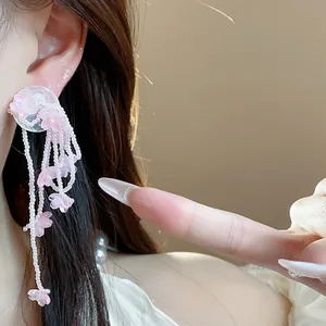 Detailed view of pink glass flower tassel earrings on model