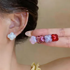 Detailed view of colorful four-leaf clover stud earrings with a pearly finish