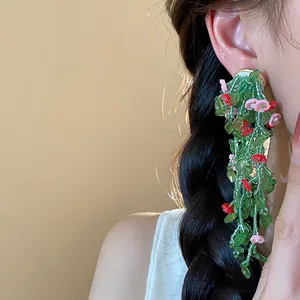 Detailed view of forest-style long tassel earrings with green glass leaves and pink flowers