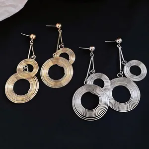 Exaggerated multi-layered circular wire-wrap metal drop earrings in gold and silver colors.