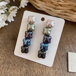 Macro detail of pearlescent flower drop earrings showing gradient pearly colors on white card