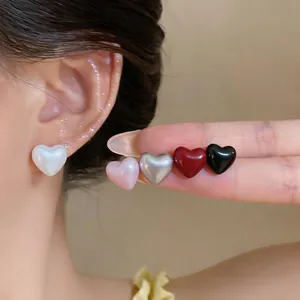 Detailed view of glossy heart-shaped stud earrings featuring multiple pearlescent color options