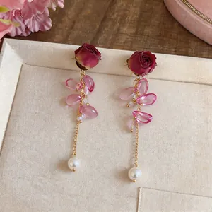 Detail view of elegant red rose eternal flower earrings with pink petals and pearl
