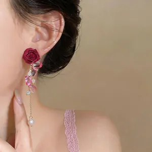 Close-up of elegant rose drop earrings with pink petals and pearl tassel on a model
