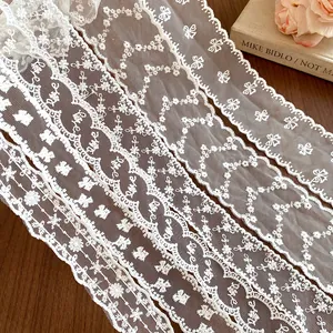 Detailed macro view of multiple white French-style lace ribbon scarves with elegant embroidery.