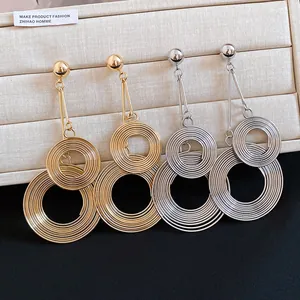 Detailed view of oversized layered concentric circular metal earrings in gold and silver.