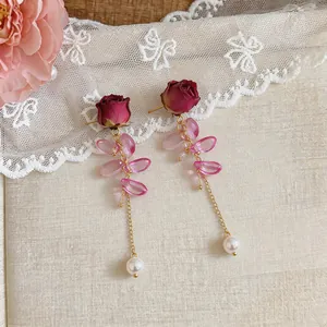 Detail view of romantic pearl tassel earrings with real dried rose and pink crystal leaves